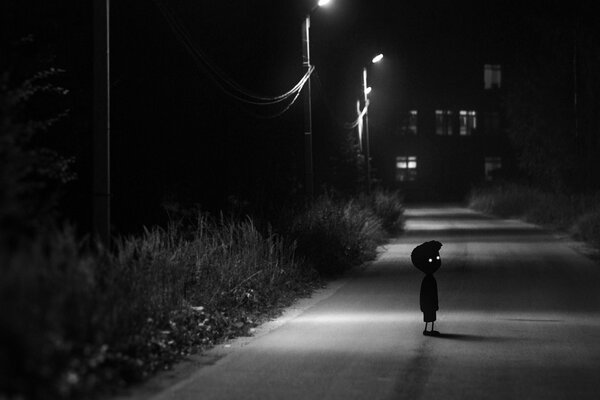 A kid on a dark street in the middle of the city