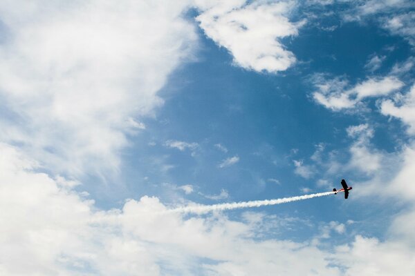 Un avión de maíz vuela en las nubes y deja un penacho