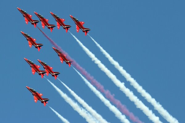 Air show of nine planes with a red arrow