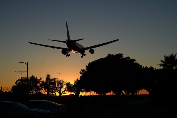 Un avión de pasajeros vuela en la distancia en medio de la puesta de sol