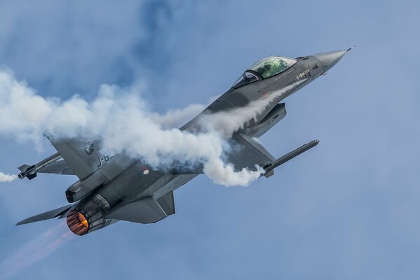 A multi-purpose fighter is flying through the sky in smoke