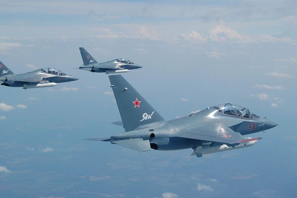 3 aviones de ataque vuelan en el cielo a la altura de las nubes