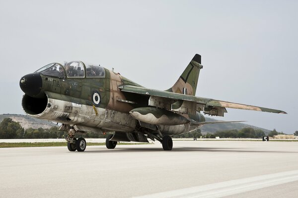 A green attack aircraft stands at the airfield