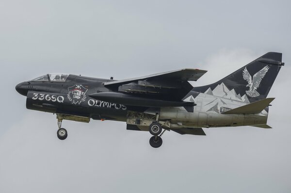 The decorated a-7n plane flies into the gray sky