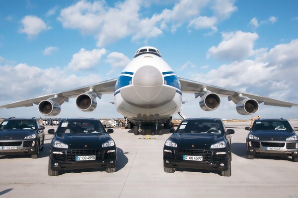 Samolot towarowy Antonov na lotnisku otoczony samochodami Porsche