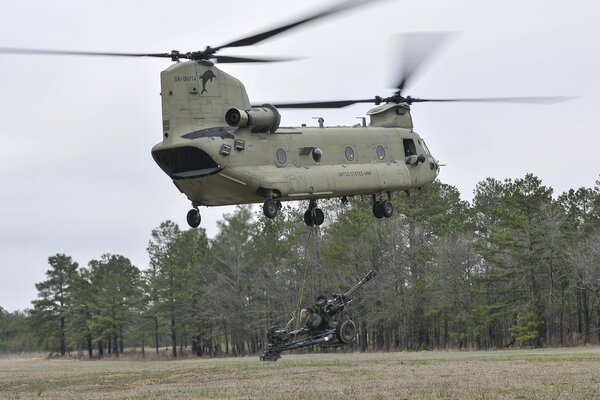 A military transport plane in the sky delivers a howitzer