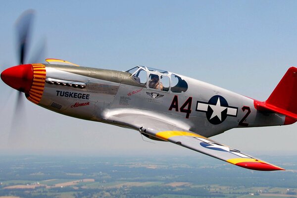 A plane flying through the sky with a fighter pilot