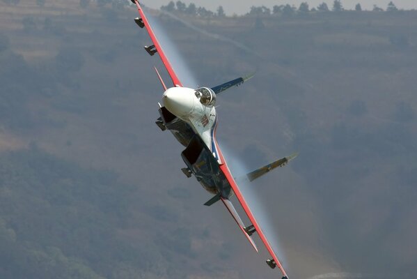 A plane plowing through the clouds against the background of hills