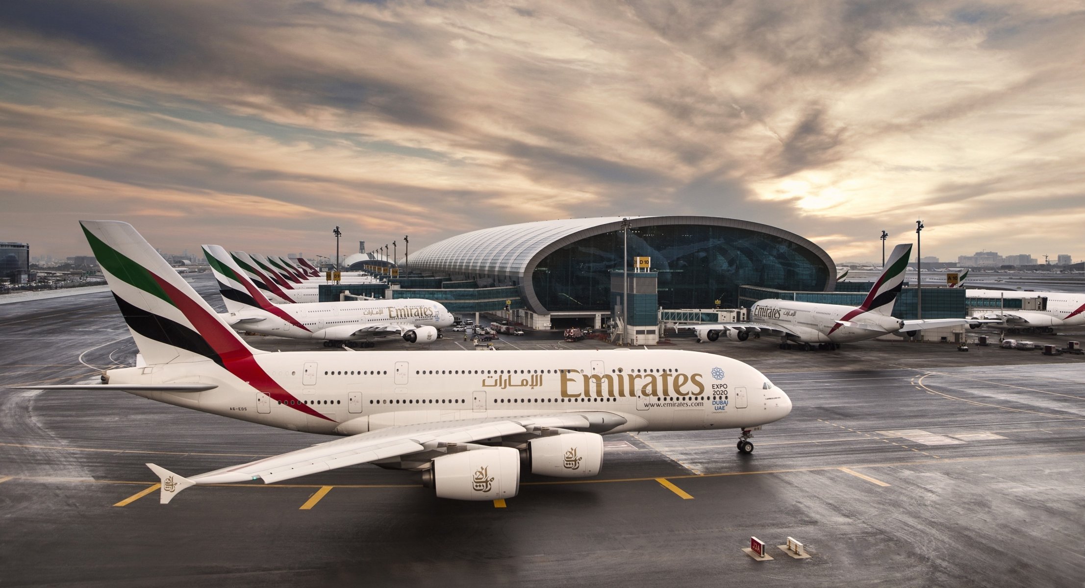 авиакомпания emirates аэробус а380 авиалайнер самолет пассажирский аэропорт дубай оаэ здание терминал восход небо облака пассажира