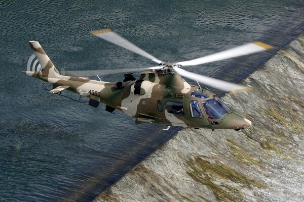 Hélicoptère Italien agusta avec peinture camouflage survolant la rivière