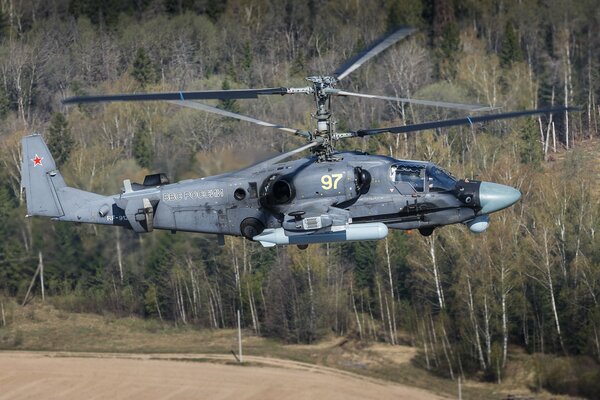 A military helicopter is hanging low over the ground