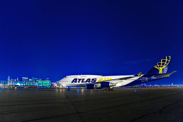 Рядом с ночными огнями в аэропорту в лас-вегасе в сша стоит бело-синий самолет
