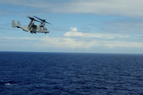The flight of a military helicopter over the boundless depths of the sea