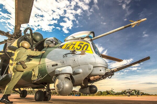 The pilot climbs onto his helicopter at the airfield