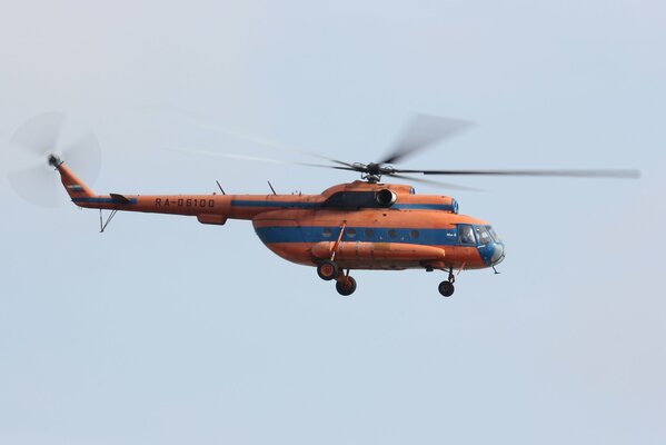 Rosyjski śmigłowiec wielozadaniowy w pomarańczowo-niebieskim kolorze na tle nieba Mi-8.