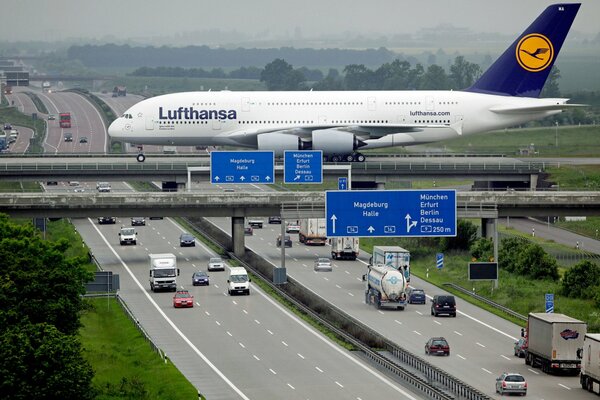 Weißes großes Flugzeug fliegt über die Autobahn