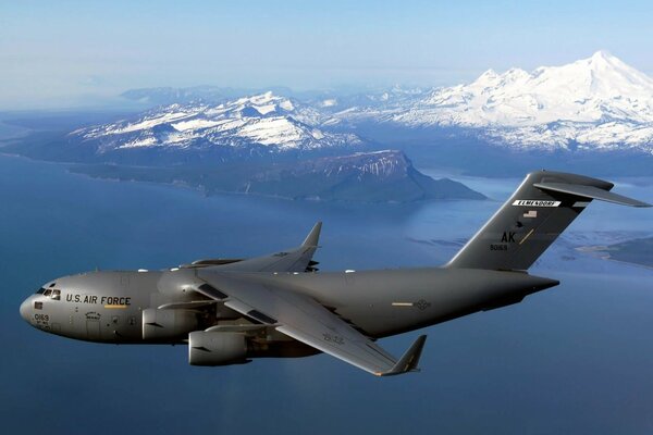 Boeing américain en vol au-dessus de la mer et des collines enneigées