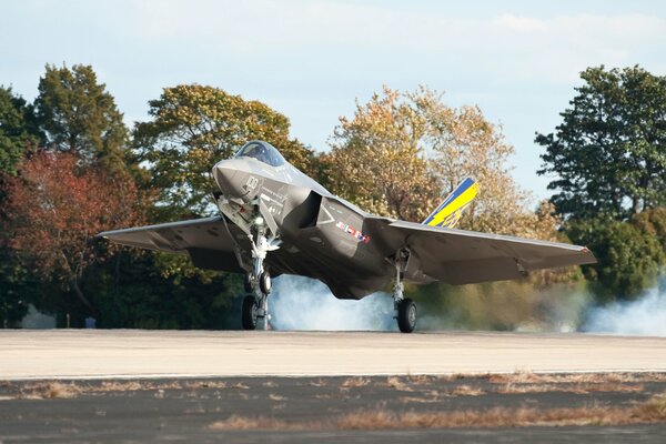 Un gros avion de chasse atterrit avec de la fumée