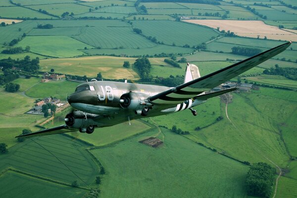 Douglas military transport plane flies over the field