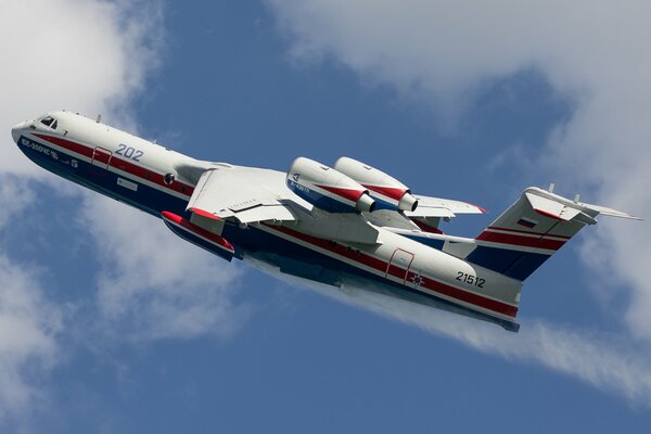 A white plane with a blue and red stripe is flying in the sky