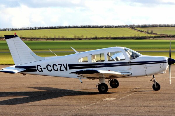 Avion blanc avec deux bandes noires sur la piste