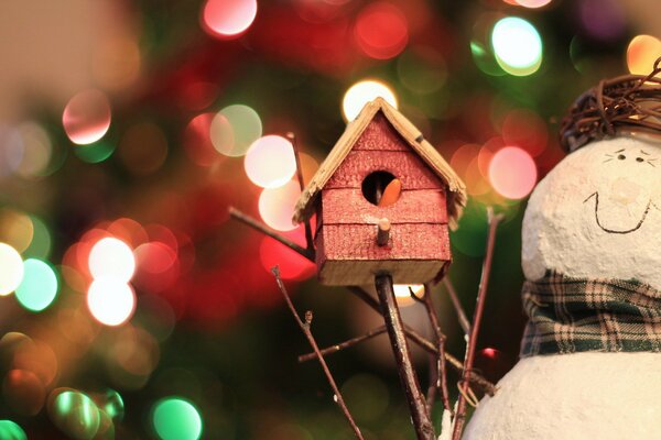 Juguetes navideños muñeco de nieve y pajarera en el fondo de la guirnalda