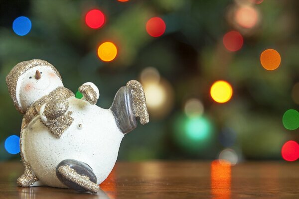 Новогодняя игрушка снеговик на фоне украшенной ёлки