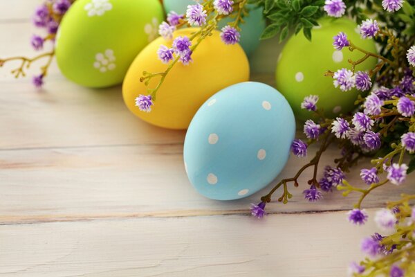 Easter eggs lie next to a branch with purple flowers