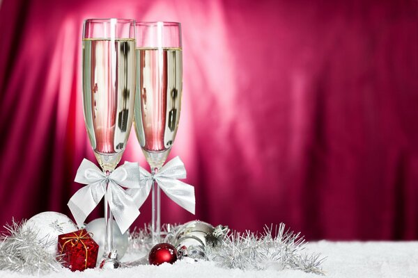 Two glasses of champagne with white bows on a crimson background