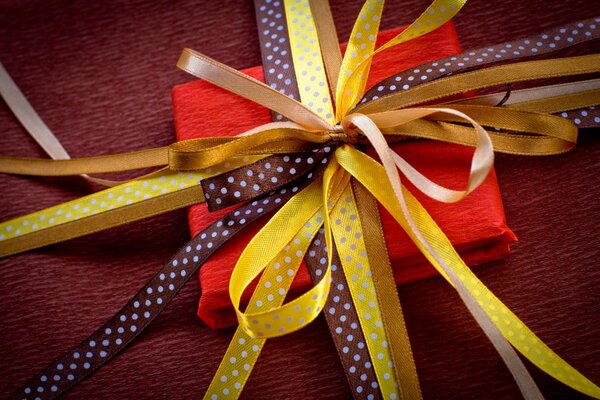 The red square gift box is tied with yellow ribbons