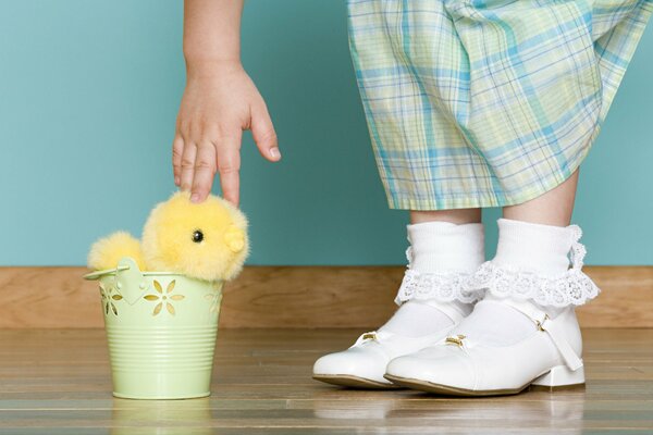 A girl with white socks reaches for a bucket