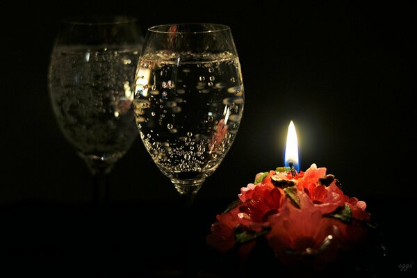 A glass of champagne with a candle by the mirror