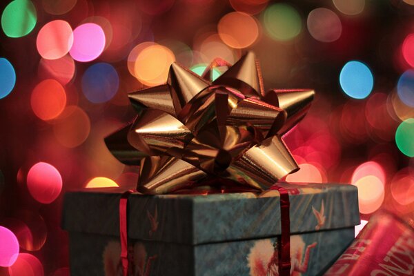 Gift box with a bow on the background of a twinkling garland