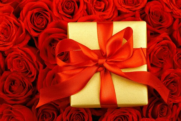 Golden gift box on a background of scarlet roses