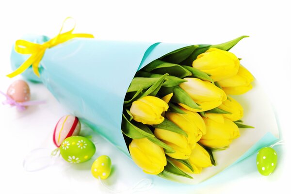 Un ramo de tulipanes amarillos sobre el fondo de los huevos de Pascua