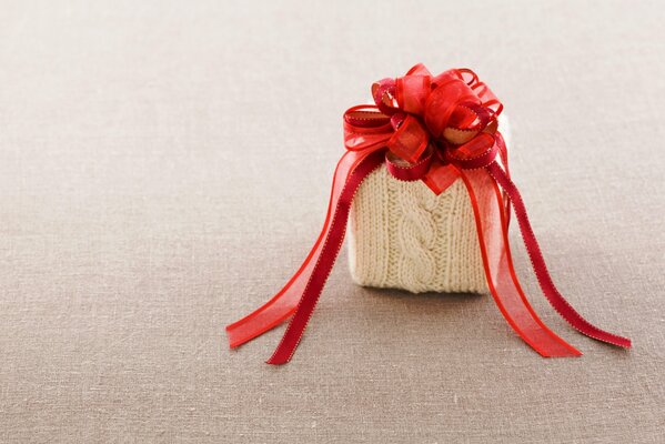 A gift in a knitted box with a red bow