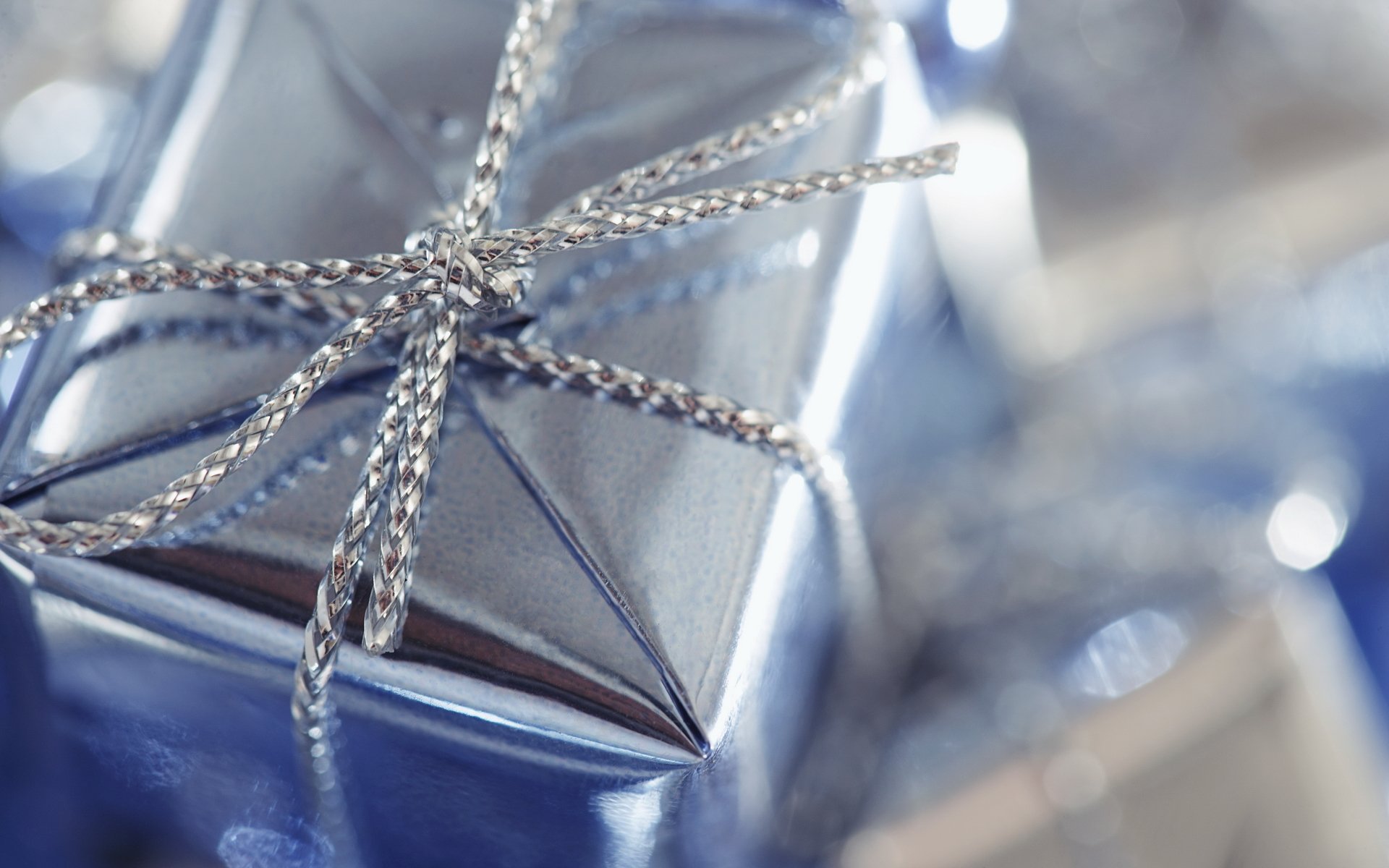 holiday present box blue packaging wrap silver pigtail weave bow node reflections close up