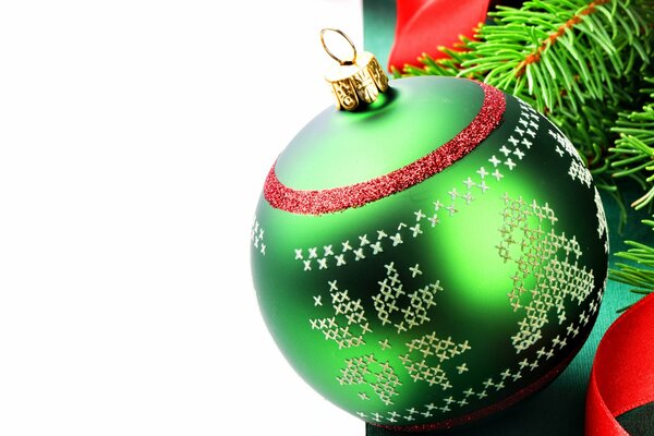 A green ball with a pattern is hanging on the Christmas tree