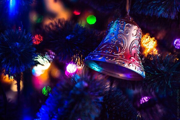 Christmas tree toy in the form of a bell on a branch of a Christmas tree