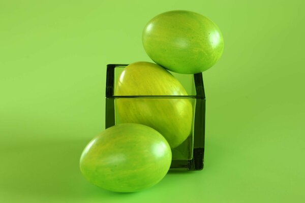 Huevos de Pascua sobre un fondo verde con un vaso