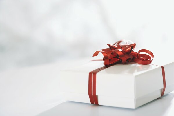 A white gift box tied with a red ribbon and a bow