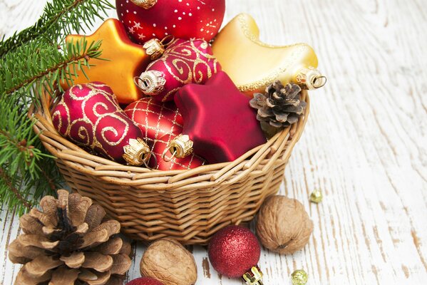 Decorazioni natalizie rosse e dorate in un cesto con coni e noci su una tavola di legno
