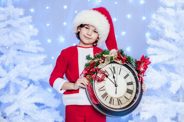 A boy in a Santa hat holds a watch