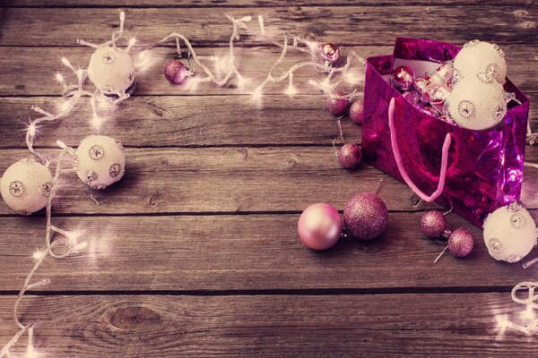 Guirnalda de Navidad rosa con bolas luminosas en el piso de madera