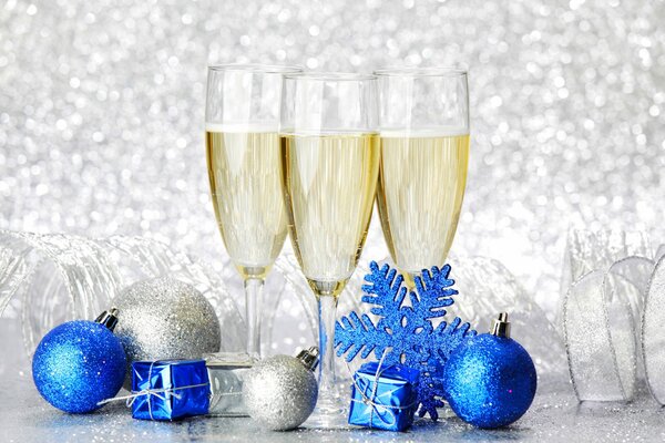 Giocattoli di Natale blu e argento e tre bicchieri di champagne