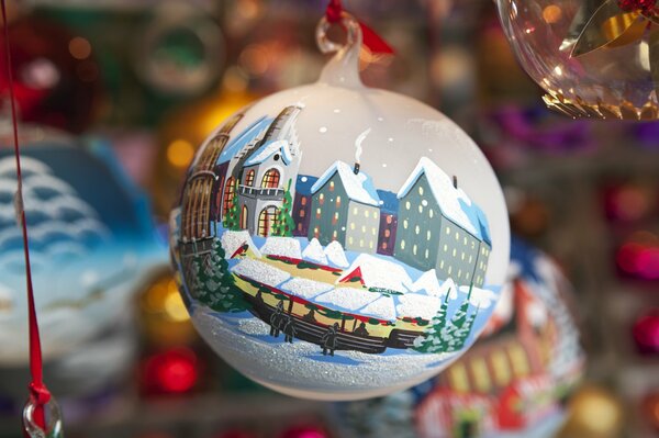 Die Weihnachtskugel ist mit Häusern und Weihnachtsbäumen mit Hütten mit Schnee bemalt