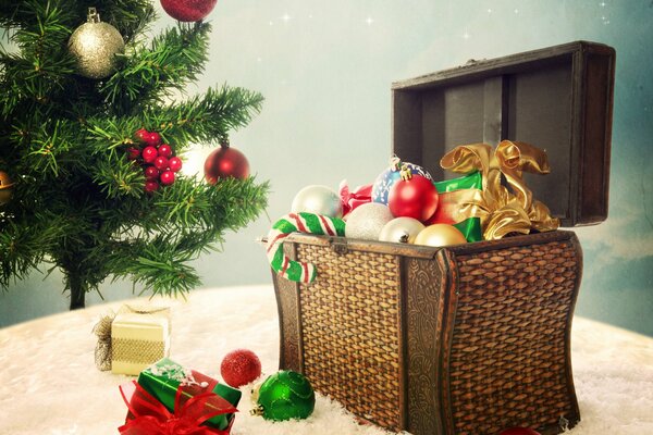 Paesaggio di Natale con una scatola di decorazioni per l albero di Natale su un plaid soffice beige e abete verde decorato con giocattoli