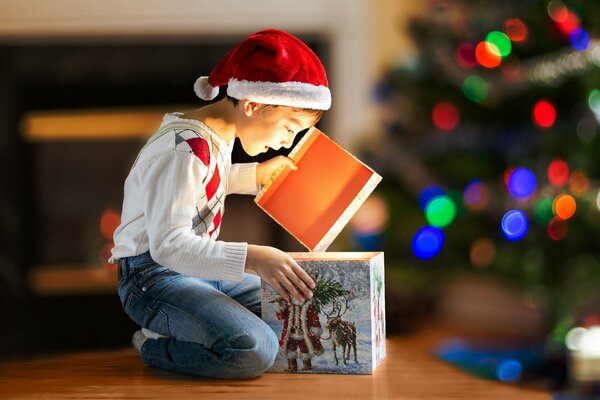 Il ragazzo apre il Suo regalo tra le luci di Natale