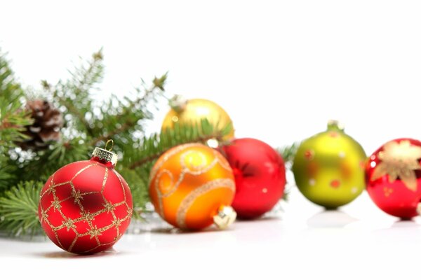 Multicolored Christmas balls and a fir branch with a cone on a white background