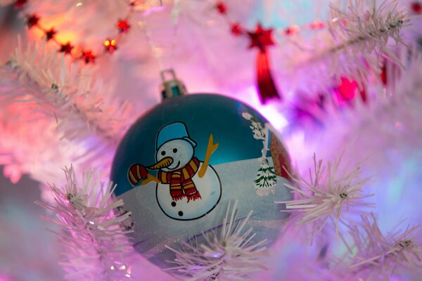 Bola de juguete de Navidad con muñeco de nieve, colgando en el árbol de Navidad blanco